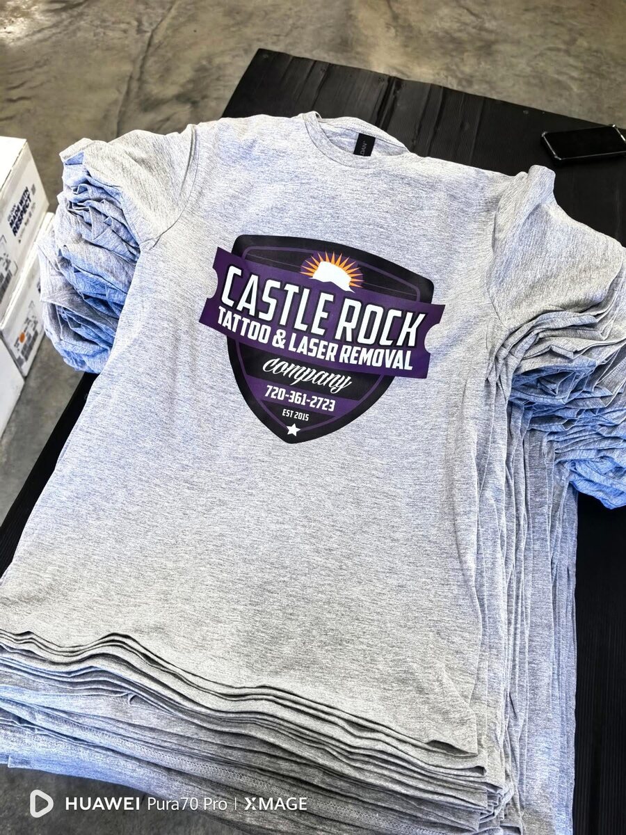 Stack of custom gray business T-shirts with a purple logo