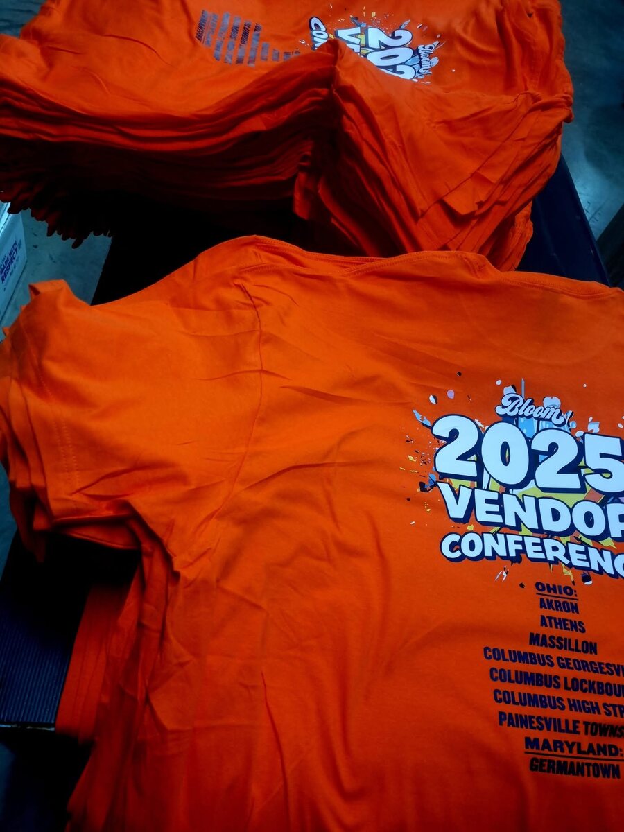 Stacks of bright orange custom conference T-shirts